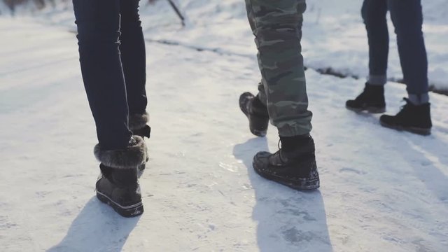 Feet walking in the snow with tracking shoes. Friends walking on snow road 
