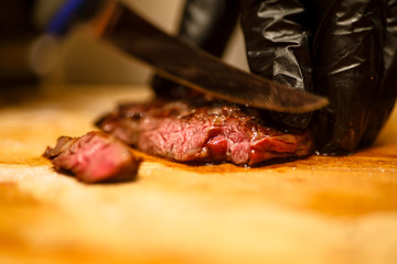The chef cuts beef steak roasting rare.