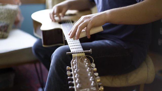 Shallow depth of field with focus on slider of six string slide guitar.