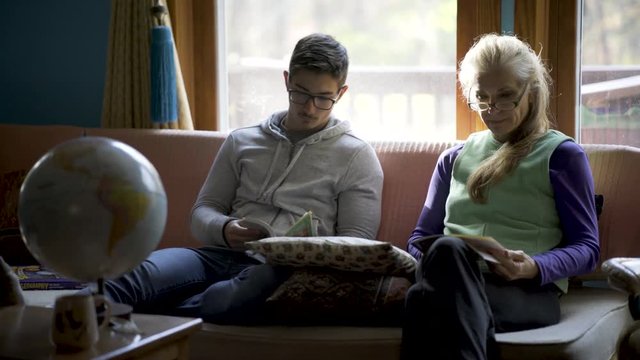 Homeschooling teenage boy and mother discuss art history and geography with a globe of the world in front of them for reference in a relaxed living room atmosphere.