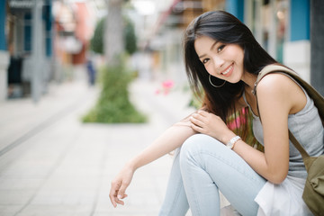 Summer sunny lifestyle fashion portrait of young stylish hipster woman sitting on the street, wearing cute trendy outfit