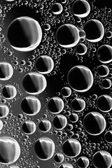 Round drops of water with glare on a dark glass