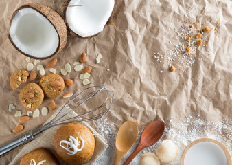 Creative composition coconut cookies and bun with almond, flour, sugar and wooden spoon on brown paper background.