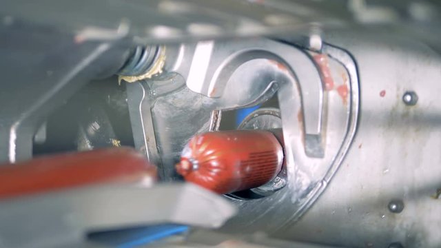 Packaged sticks of sausage are being cut off from each other by a machine