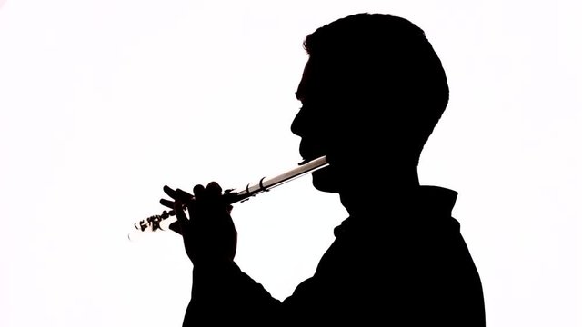 Isolated silhouette of a guy playing the flute. Black and white footage.