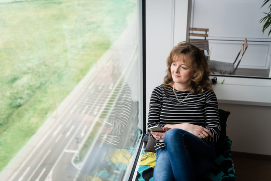 Lady at home sitting near window and relaxing