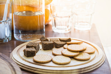 Dry biscuits and corn bread as food sample. Biscuits and dark bread for degustation on a wood plate and water jar