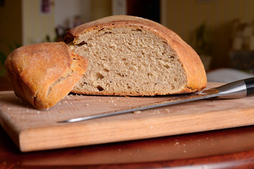 fresh bread with a crisp on a wooden board with a knife