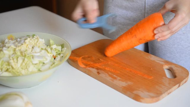 The cook cleans carrots for salad.