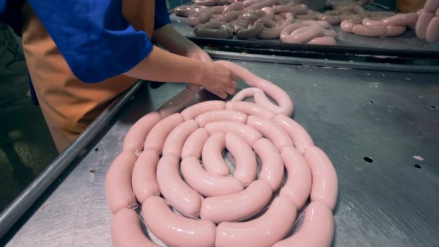 A butcher is working with a link of sausages bare handed