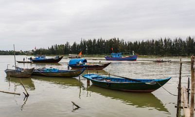 Fototapeta na wymiar 9 fishing boats in all different sizes and for different uses on river 