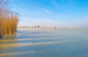 Ice skating on a frozen lake in sunlight in winter - obrazy, fototapety, plakaty