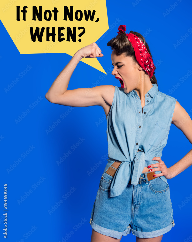 Wall mural young woman in retro clothing showing muscles and shouting with IF NOT NOW, WHEN? speech bubble isolated on blue