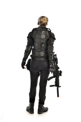 full length portrait of female  soldier wearing black  tactical armour, standing  with back to the camera holding a gun, isolated on white studio background.