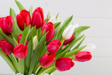 Fresh red tulip flowers bouquet on shelf in front of wooden wall.