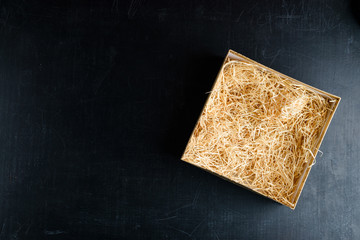 Composition with decorative straw in a box with copyspace for text on dark background. Top view,...