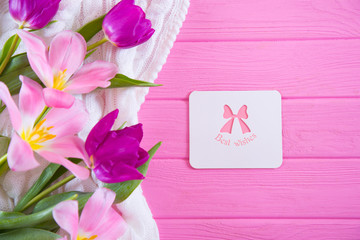 Greeting card with inscription "Best wishes" and tender bouquet of beautiful tulips on pink wooden background