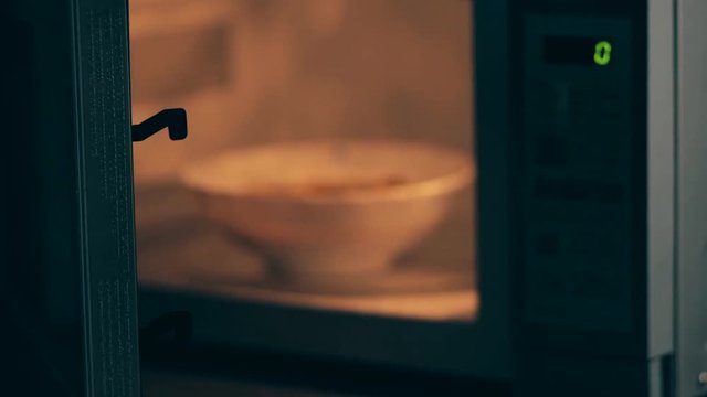 A bowl of soup is going to be heated in a microwave oven