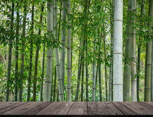 Japanese style wood board platform with background of fresh green bamboo forest in summer.