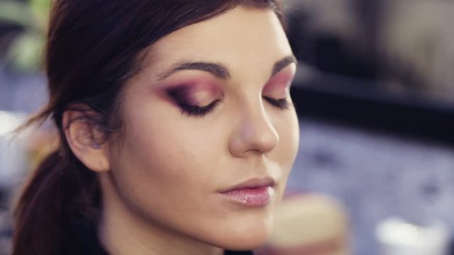 Beautiful sexy brunette girl gets her eye make up done by professional at a beauty studio.