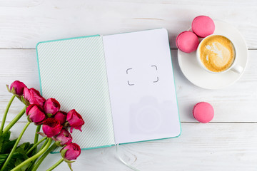 Close notebook, cup of coffee and tulips on light wooden background with copyspace. Concept of planning day, wishes, thoughts and future goals