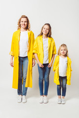 Obraz premium beautiful mother and daughters in yellow raincoats on white