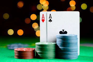 Concept of casino, playing cards and money. Stacks of poker chips and aces on green table at the casino