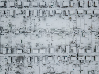 Aerial view of snow covered allotment with many tiny houses in white landscape