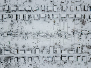 Aerial view of snow covered allotment with many tiny houses in white landscape