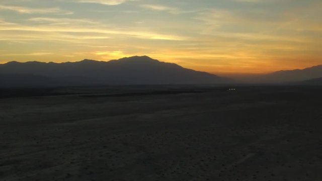 Aerial panning shot of the sunset behind mountains on the horizon