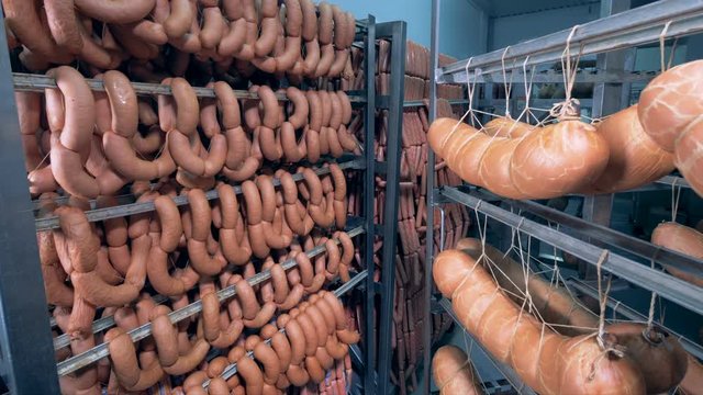 Thick and thin sausages along with large sausage sticks are hanging in a storage room