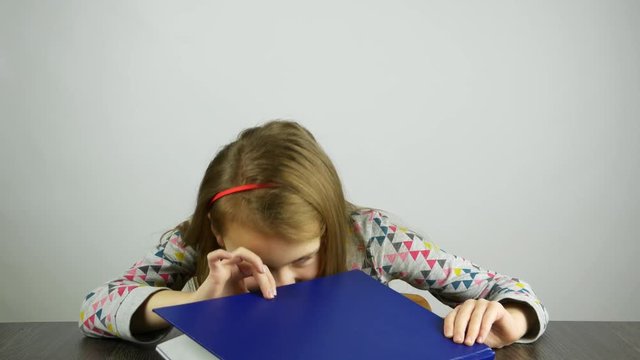 The girl peeks in the book and looks surprised. The concept of children's 