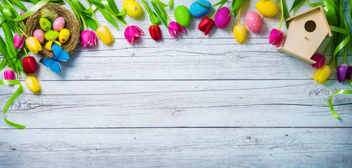 Fototapeta premium Easter background. Colorful spring tulips with butterflies and painted eggs