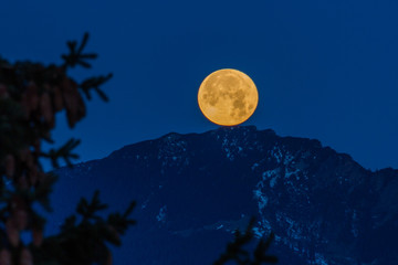 Fototapeta premium Vollmond versinkt hinter den Bergen