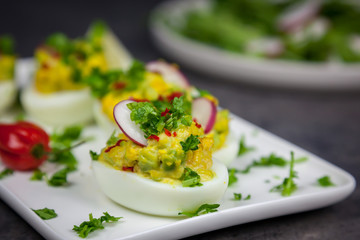 Stuffed eggs with avocado, parsley, chili and radish - healthy breakfast