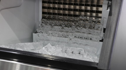 cube ice in ice making machine that door open ; to transform liquid water to solid ice  below zero  degree celsius  ; food and drink industrial background ; close up
