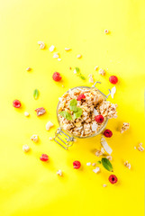 Healthy breakfast and snack concept, homemade granola with fresh raspberries in jar, on bright yellow background copy space  top view