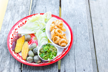 The delicious pork scratching or pork crackling snack food Thai tradition cuisine menu with herbs, yam or sweet potato boiled, cabbage, chili youth local popular meal in Chiangmai, Thailand.