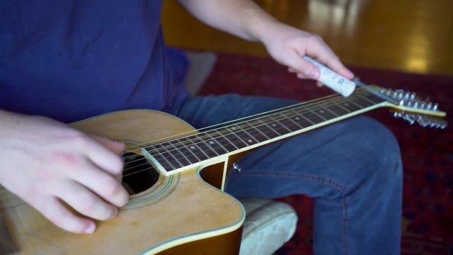 Closeup of slide guitar player picking the strings while sliding.