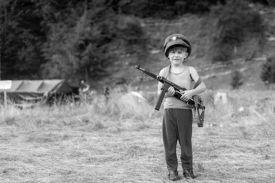 A little boy in his cap holds a trophy weapon MP-40 from the Second World War