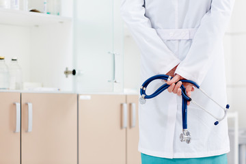 Rear view image of woman doctor holding stethoscope in a hospital