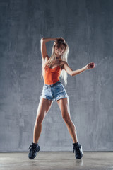 Young beautiful female dancer is posing in the studio