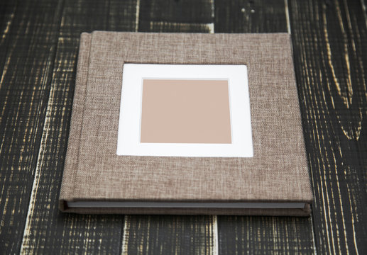 Closeup top view of family photo album isolated on brown wooden background. Horizontal flatlay photography.