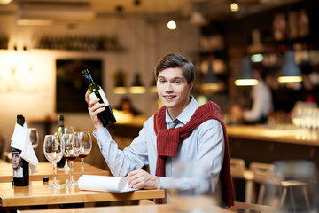 Young sommelier choosing a bottle of good wine at restaurant