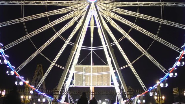 Paris ferris wheel slowly rotating night, people visit amusement park, landmark