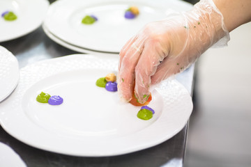 Cook decorates a plate of food with green sauce