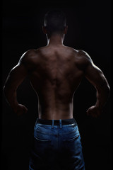 Fototapeta na wymiar Muscular man posing in studio on dark background