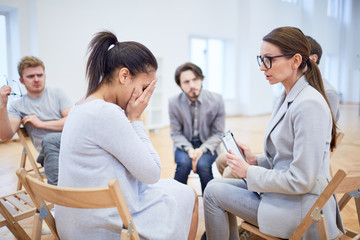 Professional psychologist consulting desperate businesswoman during session for young managers