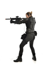 full length portrait of female  soldier wearing black  tactical armour, standing  with back to the camera holding a gun, isolated on white studio background.