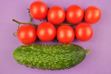 Red  cherry tomato and cucumber on a purple  background